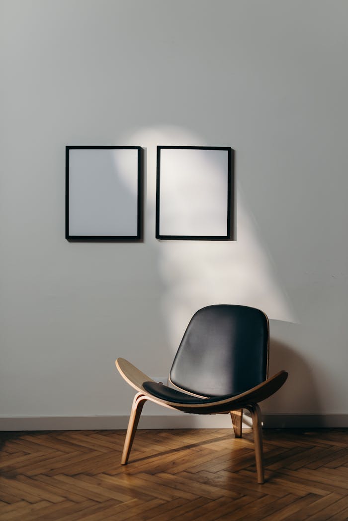 About Stylish minimalist interior with black chair and blank frames casting shadows.